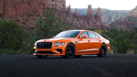 Orange Bentley Luxury Against Desert Cliffs wallpaper