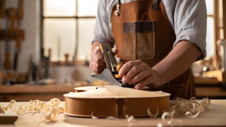 Master Crafting a Violin in Warm Workshop Light wallpaper