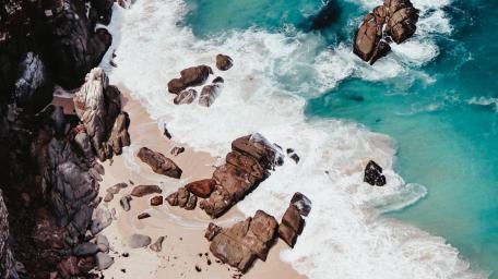 Aerial Coastal Waves Over Rocky Shore wallpaper