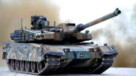 Camouflaged Battle Tank Charging Forward wallpaper