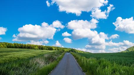 Sunny Countryside Road Under Fluffy Clouds wallpaper