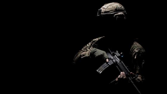 Military Silhouette in Camouflage Holding Machine Gun wallpaper