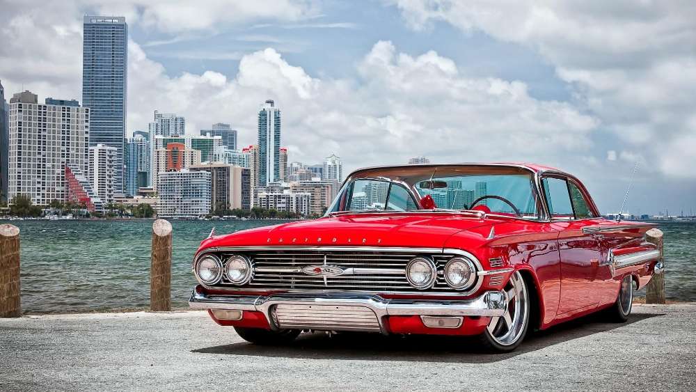 Classic Red Oldsmobile Against City Skyline wallpaper
