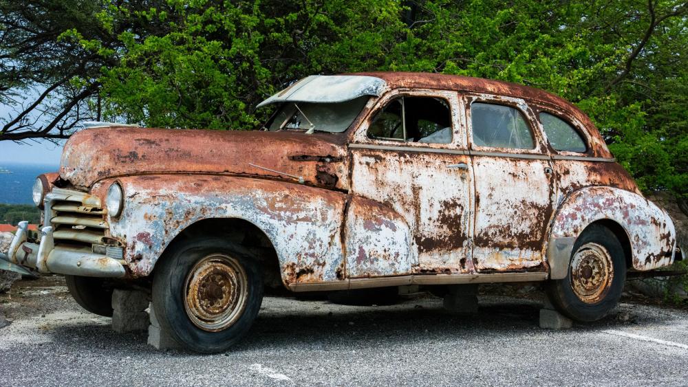 Broken rusty vintage car on bricks wallpaper
