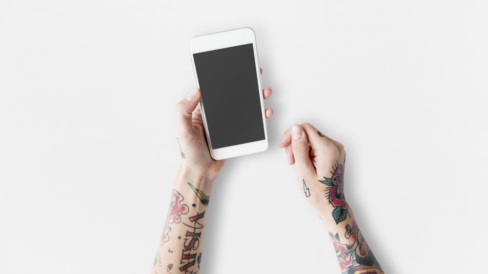 Tattooed arms with a white cell phone wallpaper