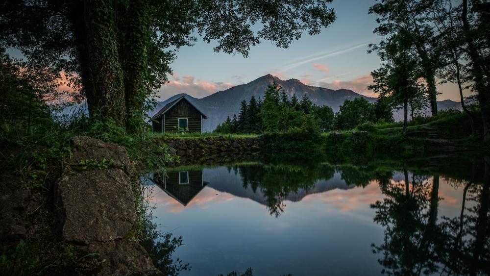 Wooden cottage reflected in a pond wallpaper