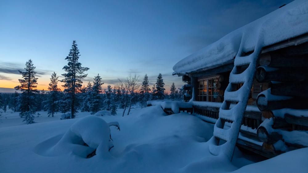 Snowy log cabin during sunset wallpaper
